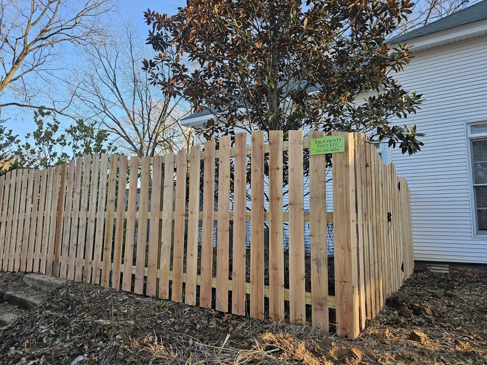 Spaced wood picket fence beside a white house