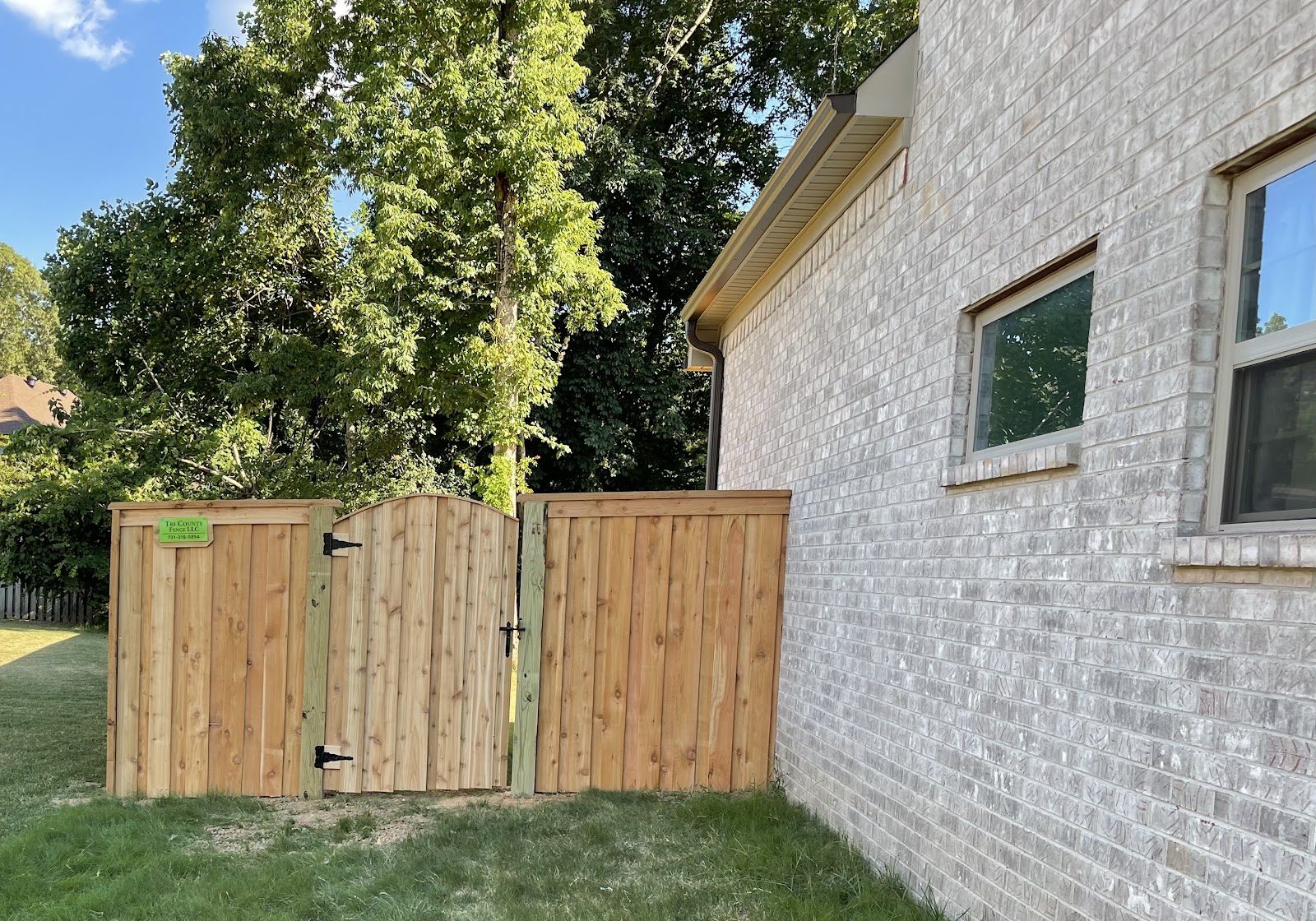 Wood privacy fence and gate beside a brick home